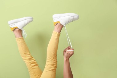 Arka planda ayakkabı bağcıkları bağlayan genç kadın.