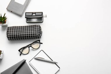 Beyaz arkaplanda kalem kutusu, gözlük ve kırtasiye malzemesi, yakın plan