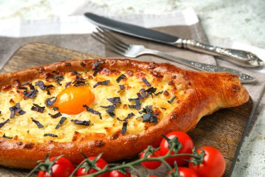 Arkaplanda lezzetli Ajarian Khachapuri olan ahşap tahta pano, yakın plan.