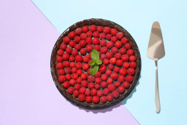 Renkli arkaplanda lezzetli ahududu turtası, nane ve spatula olan tahta