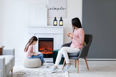 Genç anne ve kızı şöminenin yanında dinleniyor.