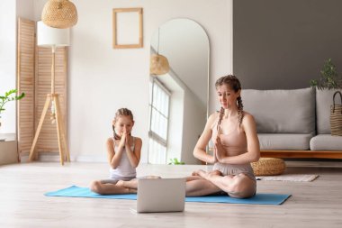 Annesiyle evde yoga yapan küçük bir kız.