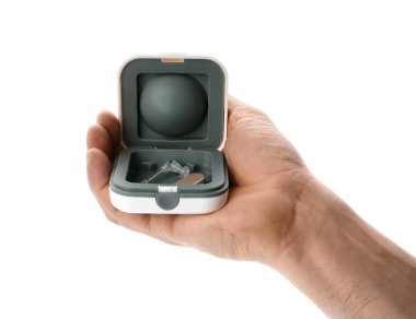 Beyaz arkaplan üzerinde işitme cihazı olan kutuyu tutan adam