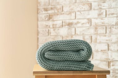 Tuğla duvarın yanında ekose örülmüş tabure, yakın plan.