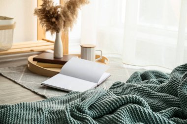 Kitaplar ve pencerenin yanında örülmüş ekoseyle dinlenmek için rahat bir yer.