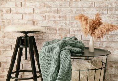 Masada yumuşak ekose, odada tuğla duvarın yanında tabure.