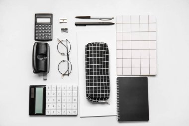 Beyaz arkaplanda kalem kutusu, gözlük ve kırtasiye malzemesi