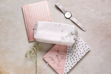 Kalem kutusu, defterler ve hafif arkaplanda kol saati.