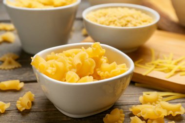 Ahşap arka planda pişmemiş creste makarna ile kase