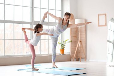 Annesiyle evde yoga yapan küçük bir kız.