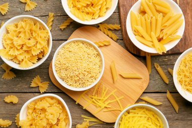 Ahşap zemin üzerinde farklı türde pişmemiş makarna.