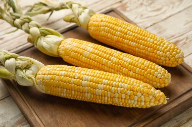 Hafif ahşap masada taze mısır koçanları.