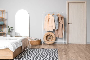 Giysileri ve aynası olan şık bir yatak odası.