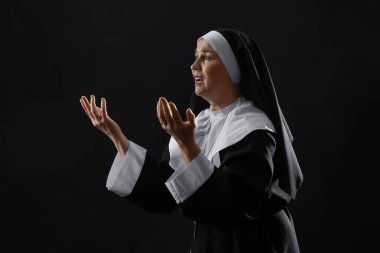 Karanlık arka planda üzgün bir rahibe.