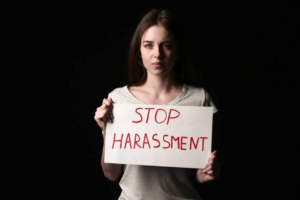 Νεαρή Γυναίκα Κρατώντας Χαρτί Κείμενο Stop Harassment Σκούρο Φόντο — Φωτογραφία Αρχείου