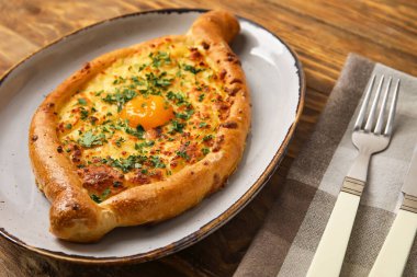 Ahşap arka planda lezzetli Ajarian Khachapuri tabağı