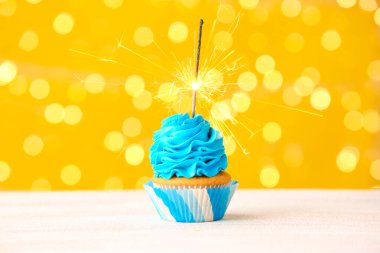 Bulanık ışıklara karşı masasında maytap olan leziz bir doğum günü keki.