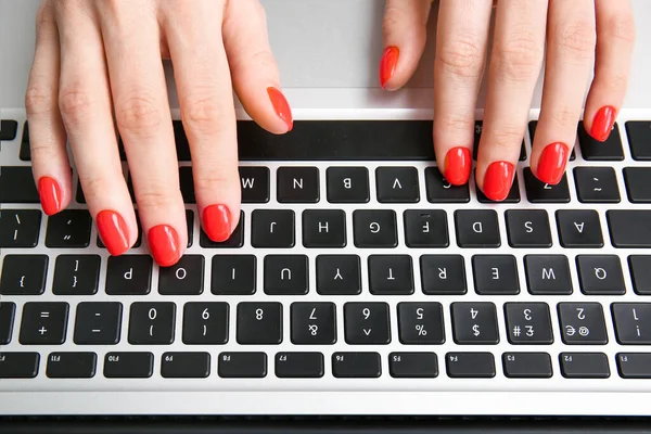 Woman with beautiful manicure working with laptop, closeup