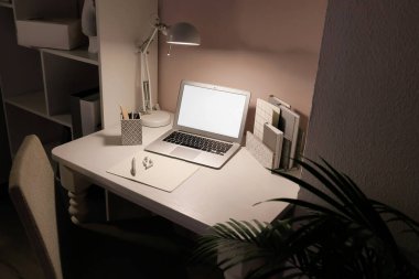 Dizüstü bilgisayarı ve ışık duvarının yanında parlayan lambası olan modern işyeri