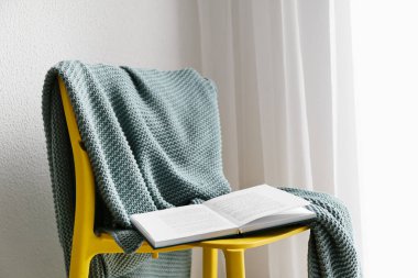 Ekoseli sandalye ve ışık duvarının yanında kitap