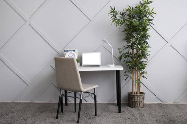 Işık duvarının yanında dizüstü bilgisayarı olan modern bir işyeri