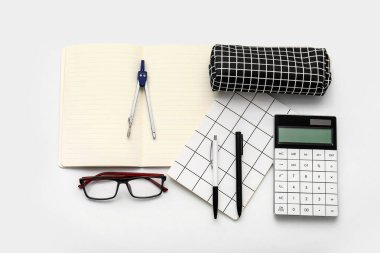 Beyaz arkaplanda kalem kutusu, gözlük ve kırtasiye malzemesi