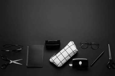 Kalem kutusu, gözlükler ve koyu arkaplan kırtasiyesi.