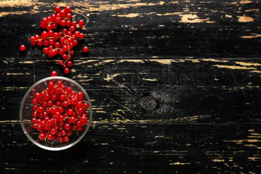 Koyu ahşap arka planda taze kırmızı üzümlü cam kase.