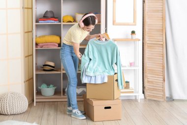 Genç bir kadın gardıropta kıyafet ayarlıyor.