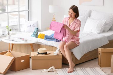 Yatak odasında giysileri düzenleyen genç bir kadın.