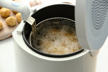 Morina pirzolaları masadaki fritözde hazırlanıyor, yakın plan.