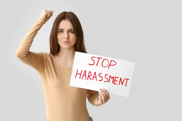 Jovem Segurando Papel Com Texto Stop Harassment Fundo Cinza — Fotografia de Stock