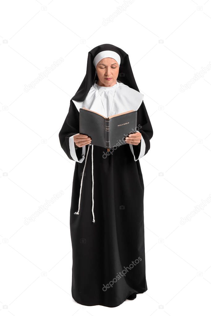 Mature nun reading Holy Bible on white background