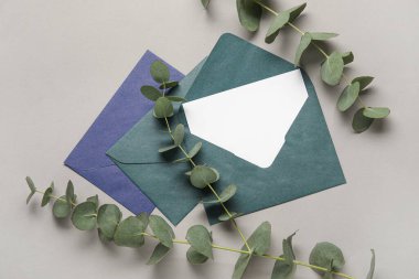 Boş kartlı zarflar ve gri arkaplanda okaliptüs.