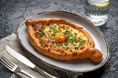 Koyu arkaplanda lezzetli Ajarian Khachapuri tabağı