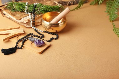 Renkli arka planda Tibet şarkı kasesi, değerli taşlar, boncuklar ve Palo Santo ile kompozisyon