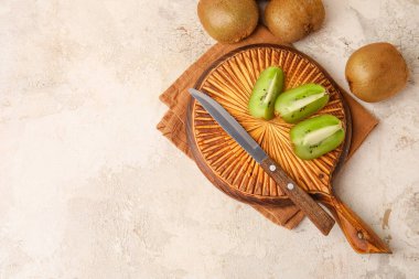 Arka planda taze kivi meyvesi ve bıçağı olan tahta.