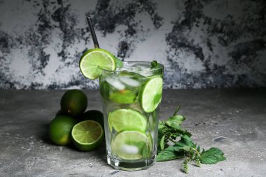 Bir bardak taze mojito, limon ve nane arkaplanda.