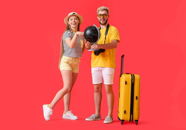 Couple of tourists with globe on color background