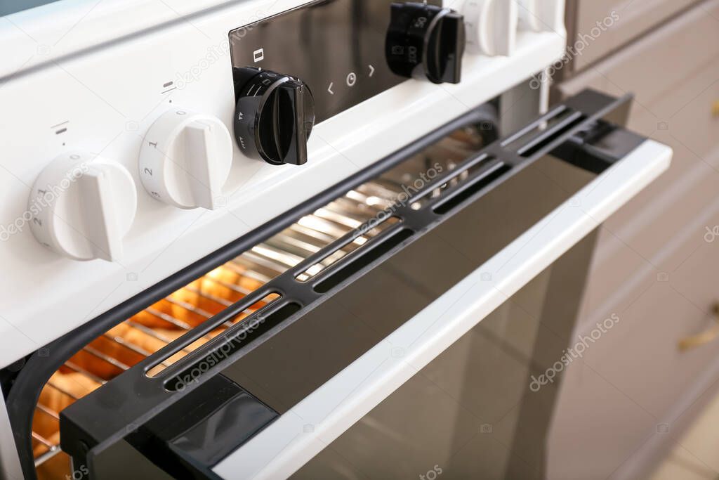 Modern electric oven with croissants in kitchen, closeup