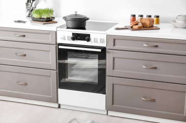 Işık duvarının yanında elektrikli fırın olan modern mobilyalar.