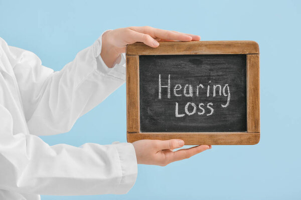 Женщина-врач держит доску с текстом СЛУШАЯ потеря на цветном фоне