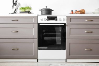 Işık duvarının yanında elektrikli fırın olan modern mobilyalar.