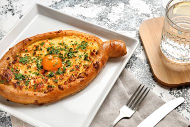 Arkaplanda lezzetli Ajarian Khachapuri tabağı