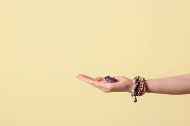 Renkli arka planda güzel bir ametist taşıyan kadın el.