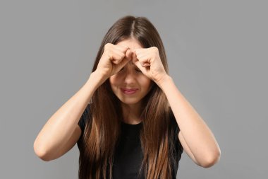 Gri arka planda korkmuş genç bir kadın. Taciz kavramı