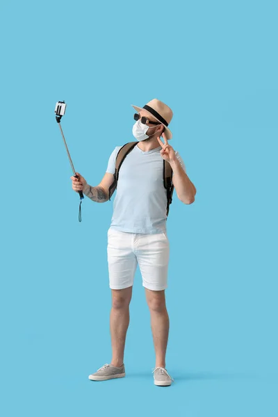 Turista Masculino Máscara Médica Tomando Selfie Fundo Cor — Fotografia de Stock
