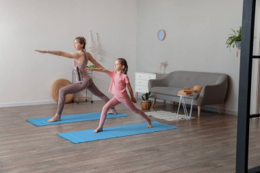 Annesiyle evde yoga yapan küçük bir kız.