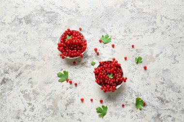 Taze kırmızı üzümlü kaseler ve açık arkaplanda yapraklar