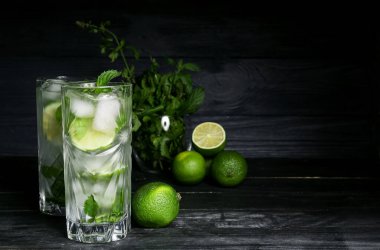 Koyu ahşap arka planda taze mojito, limon ve nane.